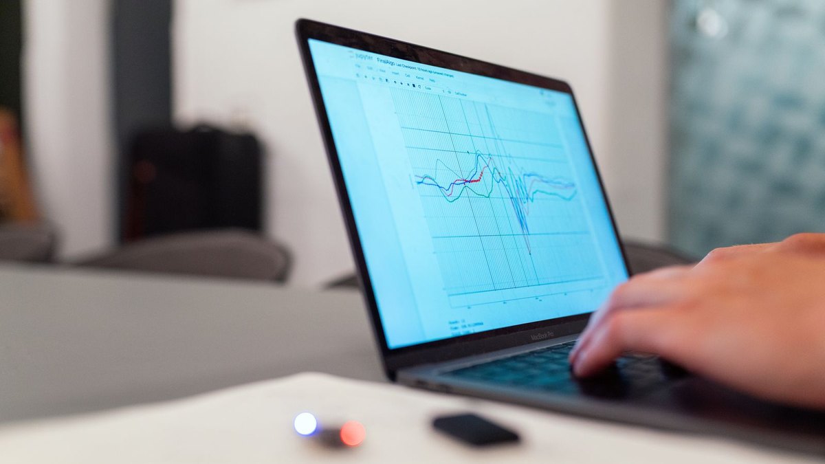 A person working at a laptop showing a line chart with a sharp downward spike in the data
